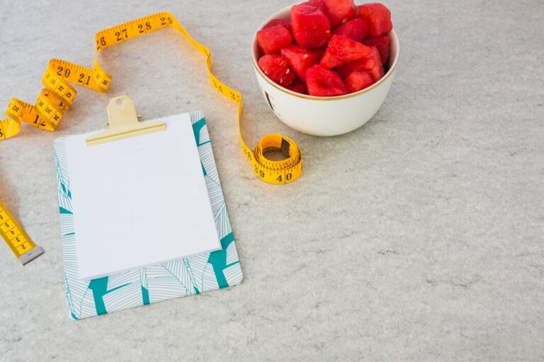 blank-paper-attached-clipboard-with-measuring-tape-watermelon-cubes-bowl_23-2147920984