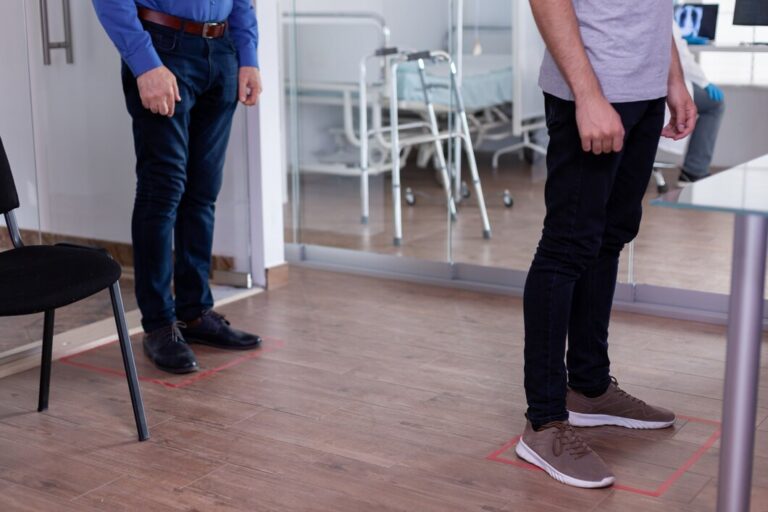 close-up-patients-standing-waiting-area-floor-signs-respecting-social-distancing-against-coronavirus_482257-2004