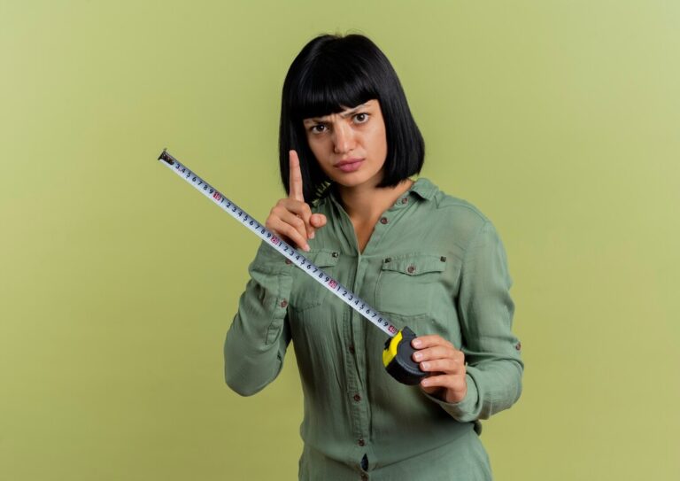 unpleased-young-brunette-caucasian-woman-holds-tape-measure-points-up-isolated-olive-green-background-with-copy-space_141793-70117