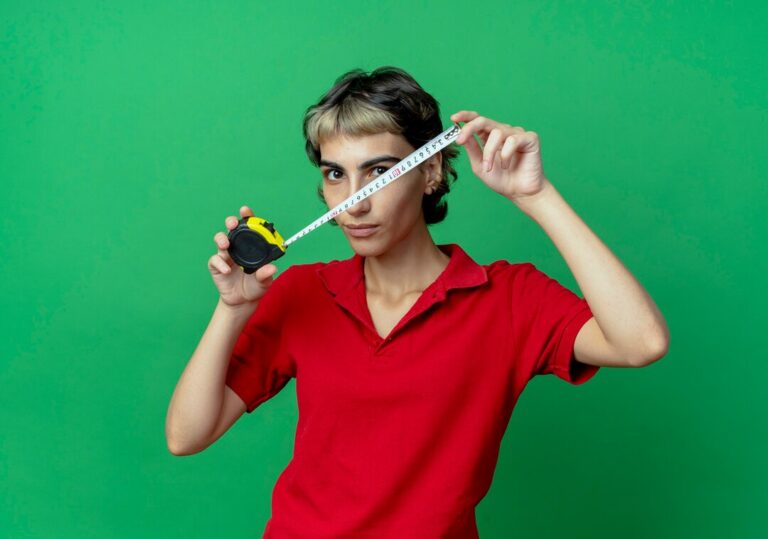 young-caucasian-girl-with-pixie-haircut-holding-tape-meter-looking-camera-isolated-green-background-with-copy-space_141793-87914