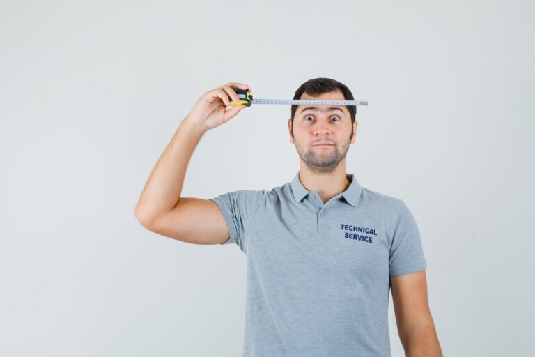 young-technician-grey-uniform-holding-measuring-tape-against-his-head-looking-serious_176474-35304